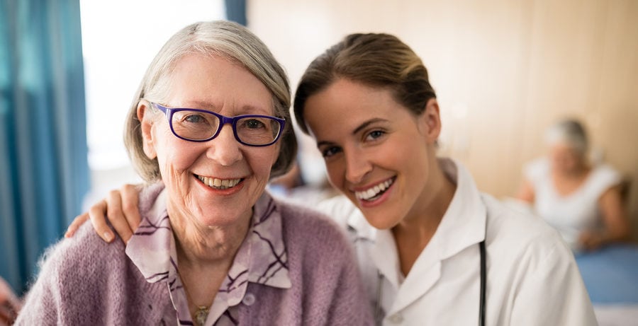 Portrait of smiling female doctor standing arm around senior woman