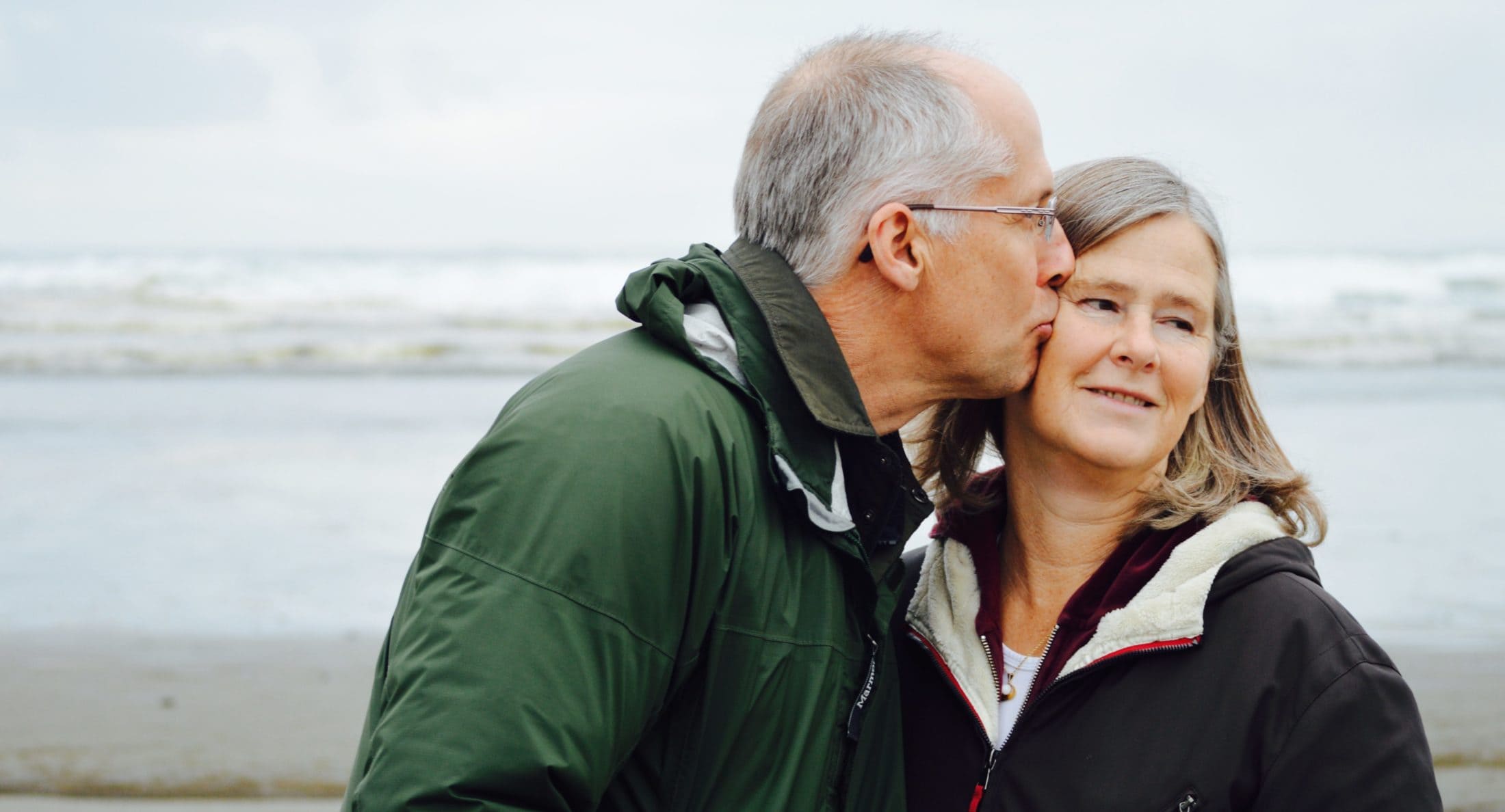senior man and woman kiss on the beach