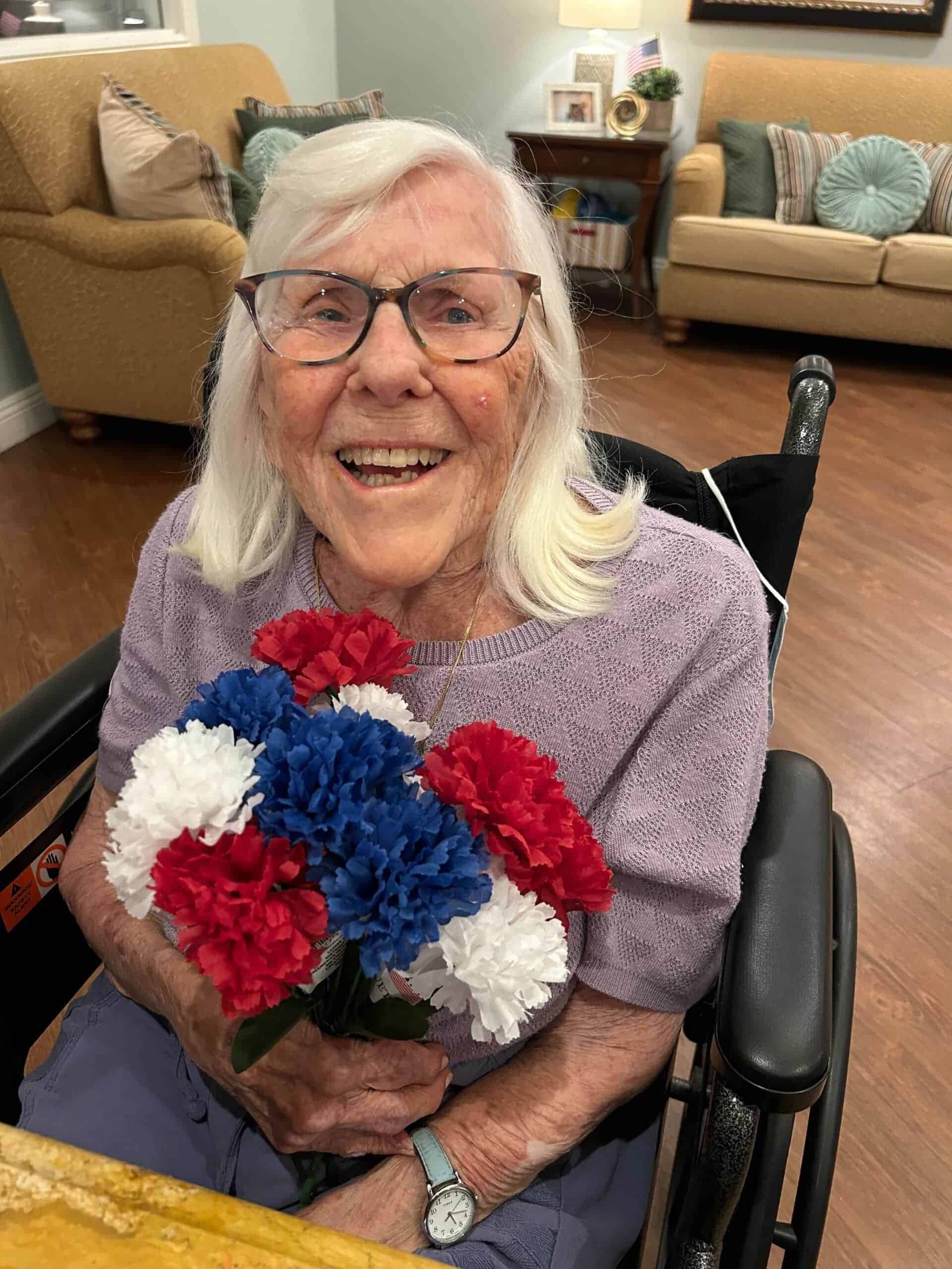 resident smiling with red white and blue flowers