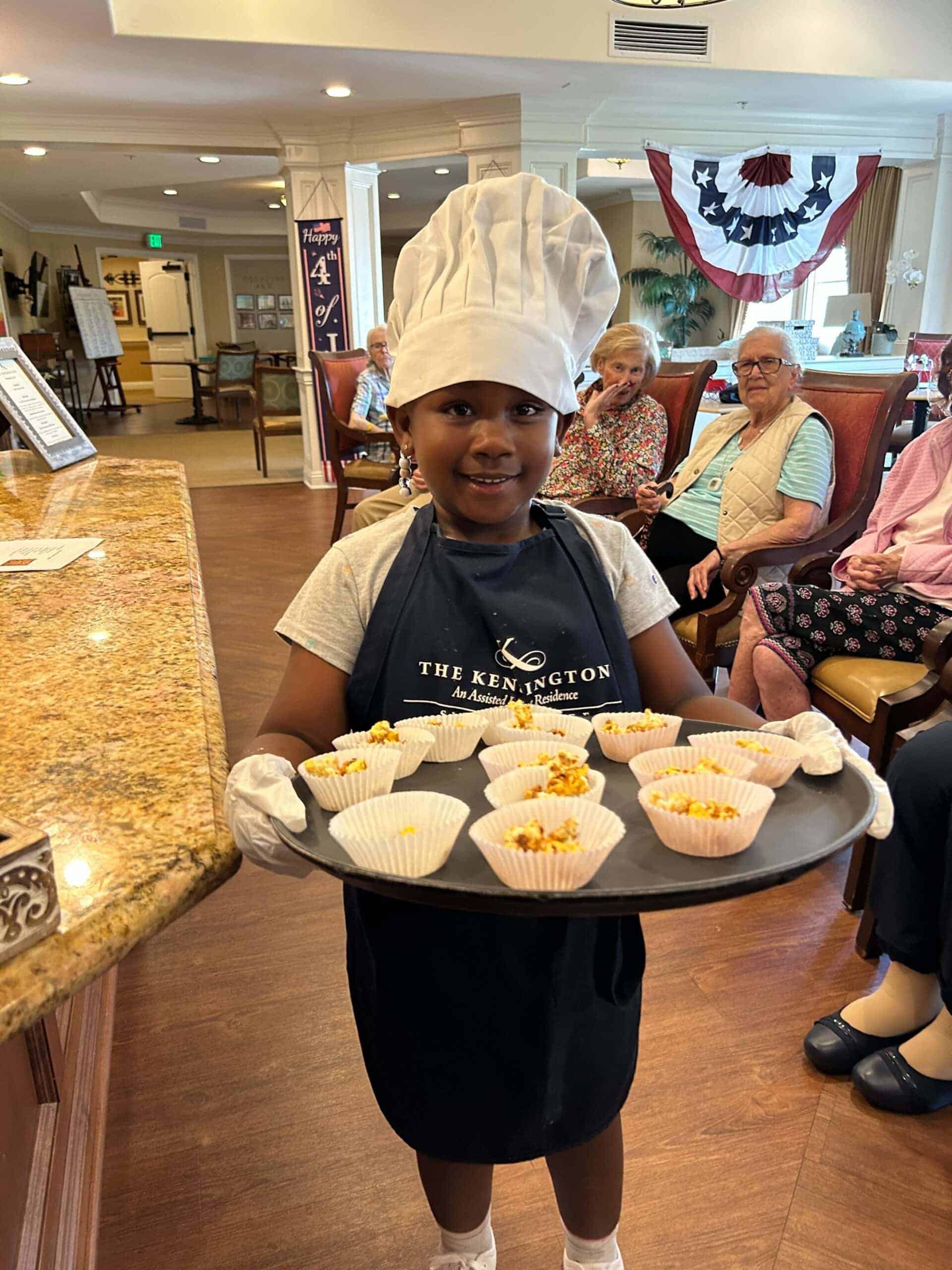 young kid holding tray of treats