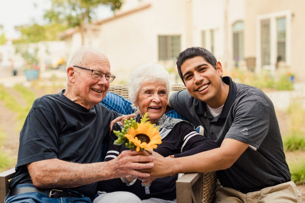 older couple and young man holding flowers