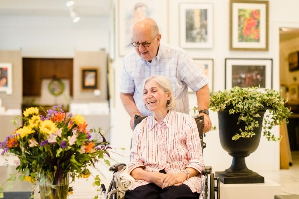 older man pushing older woman in wheelchair